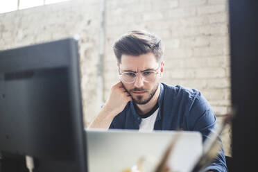 Male IT professional thinking while working on computer codes in laptop at workplace - MASF13329