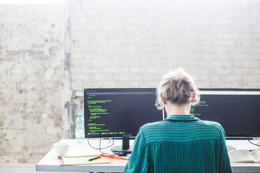 Rückansicht einer jungen Computerprogrammiererin bei der Arbeit am Schreibtisch im Büro - MASF13337