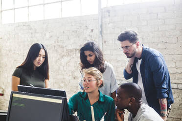 Junge Unternehmerin, die mit Hackern im Büro über Computercodes diskutiert - MASF13349