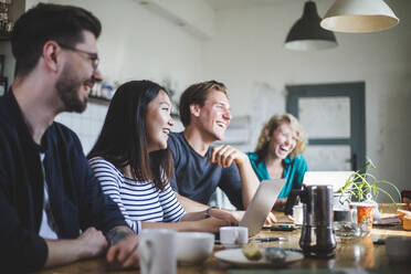 Team of professional computer hackers laughing while sitting at desk in office - MASF13389