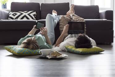 Caucasian couple using digital tablets on floor - BLEF09895