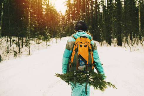 Kaukasischer Wanderer trägt Äste im verschneiten Wald - BLEF09931