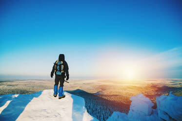 Wanderer bewundert die Aussicht von einer verschneiten Bergkuppe - BLEF09935