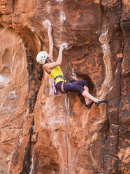 Gemischtrassiges Mädchen beim Klettern am Felsen - BLEF09959
