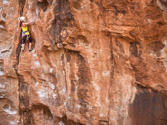 Gemischtrassiges Mädchen beim Klettern am Felsen - BLEF09960