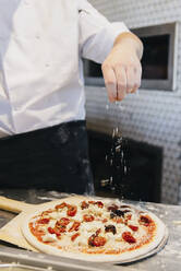 Chefkoch beim Pizzabacken im Restaurant in der Küche - BLEF09993