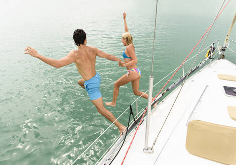 Paar springt vom Deck eines Segelbootes ins Meer - BLEF10034