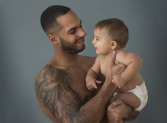 Vater mit Tattoos hält Babysohn - BLEF10060