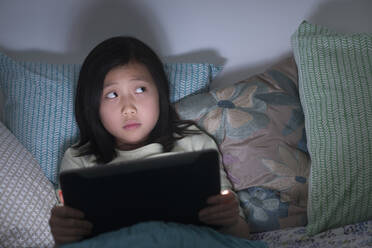 Nervöses chinesisches Mädchen beobachtet digitales Tablet im Bett - BLEF10071