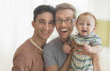 Smiling Caucasian gay fathers holding baby - BLEF10074
