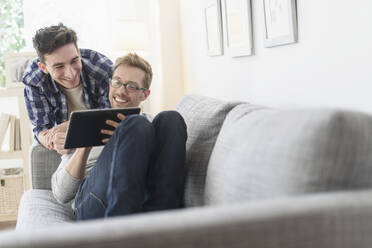 Kaukasisches schwules Paar benutzt digitales Tablet auf dem Sofa - BLEF10081