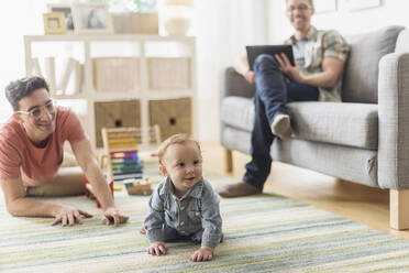 Kaukasische schwule Väter und Baby entspannen sich im Wohnzimmer - BLEF10086