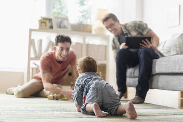 Kaukasische schwule Väter und Baby entspannen sich im Wohnzimmer - BLEF10087