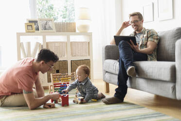 Caucasian gay fathers and baby relaxing in living room - BLEF10088