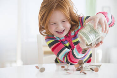 Caucasian girl pouring money from change jar - BLEF10101