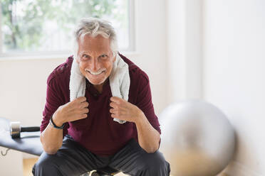 Lächelnder älterer kaukasischer Mann beim Ausruhen im Fitnessstudio - BLEF10111