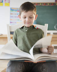 Kaukasischer Junge liest ein Buch im Klassenzimmer - BLEF10122