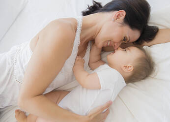 Overhead view of mixed race mother laying with baby on bed - BLEF10139