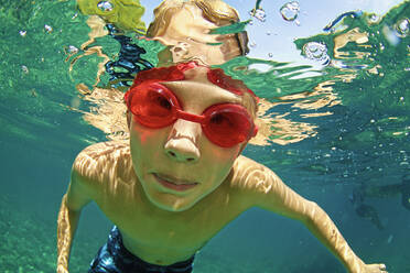 Porträt Junge mit Schwimmbrille schwimmt unter Wasser - FSIF04152