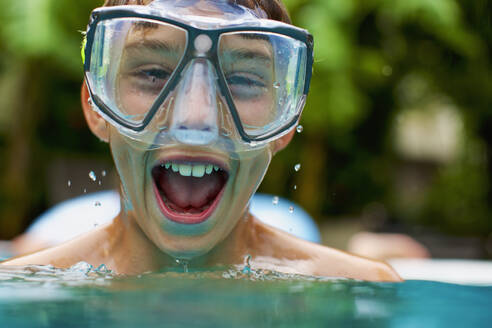 Porträt übermütiger Junge mit Schwimmbrille beim Schwimmen - FSIF04153