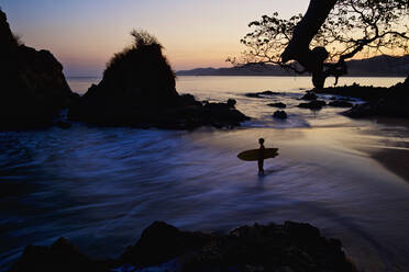 Silhouette boy with surfboard on ocean beach, Sayulita, Nayarit, Mexico - FSIF04156