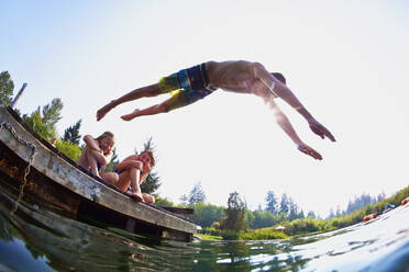 Junge springt von Steg in sonnigen Sommer See - FSIF04157
