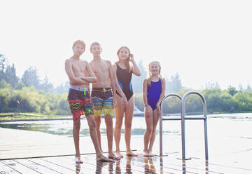 Portrait tween Freunde in Badeanzügen stehen auf sonnigen See-Dock - FSIF04162