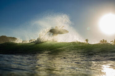 Surfer, der bei Sonnenaufgang hinter einer Welle Luft holt, Sayulita, Nayarit, Mexiko - FSIF04181