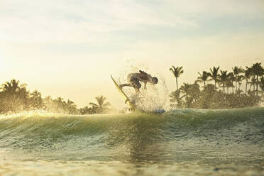 Männlicher Surfer, der bei Sonnenaufgang hinter einer Welle Luft holt, Sayulita, Nayarit, Mexiko - FSIF04196