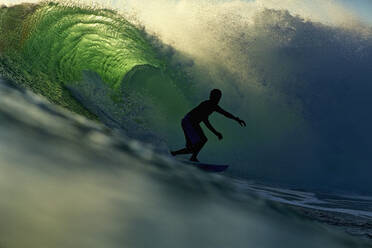 Silhouette eines männlichen Surfers auf einer beleuchteten Meereswelle - FSIF04198