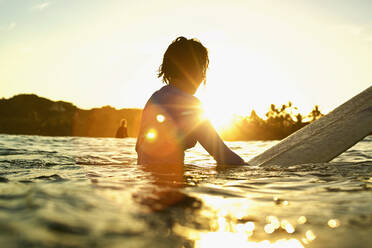 Weibliche Surferin auf dem Surfbrett auf dem sonnigen Meer bei Sonnenaufgang, Sayulita, Nayarit, Mexiko - FSIF04206