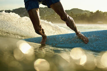 Male surfer on surfboard on sunny, sunrise ocean, Sayulita, Nayarit, Mexico - FSIF04207