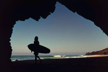 Silhouette einer Surferin in einer Höhle am sonnigen Strand, Sayulita, Nayarit, Mexiko - FSIF04210