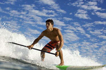 Junger Mann auf Paddleboard reitet auf einer Meereswelle - FSIF04277