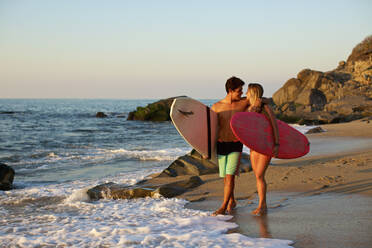 Junges, zärtliches Paar mit Surfbrettern am sonnigen Strand, Sayulita, Nayarit, Mexiko - FSIF04281