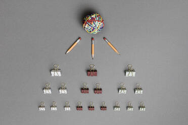 Ansichtsform über Gummibandkugel, Bleistifte und Hefterklammern auf grauem Hintergrund - FSIF04306
