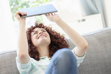 Hispanic woman using digital tablet on sofa - BLEF10170