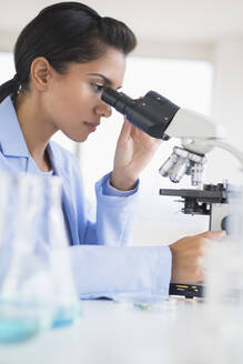 Hispanic scientist using microscope in laboratory - BLEF10204