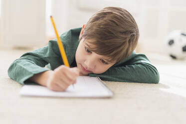 Hispanic boy doing homework on floor - BLEF10208