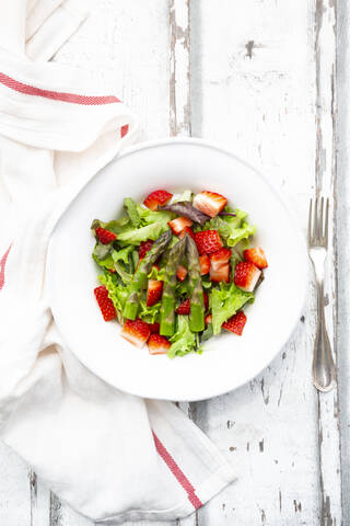 Direkt über der Ansicht von frischem Salat in einer Schüssel inmitten von Gabeln und Servietten auf einem Holztisch, lizenzfreies Stockfoto