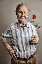 Porträt eines lächelnden älteren Mannes mit roter Rose - JATF01173