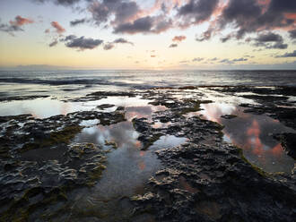 Scenic view of sea against sky seen from rocky beach at Ka'ena Point State Park during sunset - CVF01281