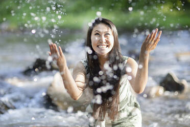 Young woman splashing in a river - SGF02402