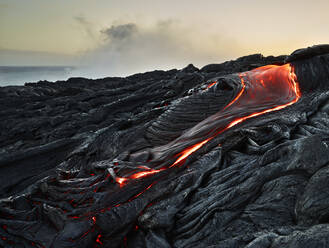 Lava, die aus dem Pu'u O'o' im Hawaii Volcanoes National Park gegen den Himmel fließt - CVF01294