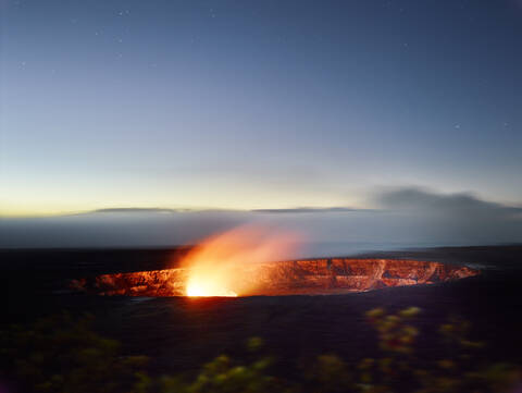 Glühender Halema'uma'u-Krater im Hawaii Volcanoes National Park gegen den Himmel in der Abenddämmerung, lizenzfreies Stockfoto