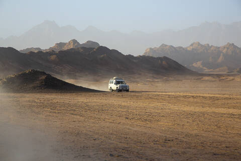 Geländewagen auf Staub in der Wüste gegen den Himmel bei Sonnenuntergang, lizenzfreies Stockfoto