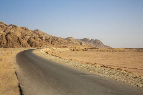 Leere Straße durch Felsformation in der Wüste gegen klaren blauen Himmel - NGF00513
