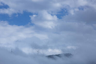 Wind turbines on mountain amidst clouds against sky - FCF01758