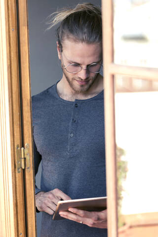 Junger Mann zu Hause, der ein digitales Tablet benutzt, lizenzfreies Stockfoto
