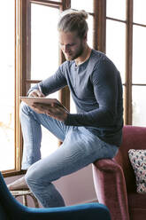 Young man at home using a digital tablet - JSRF00444